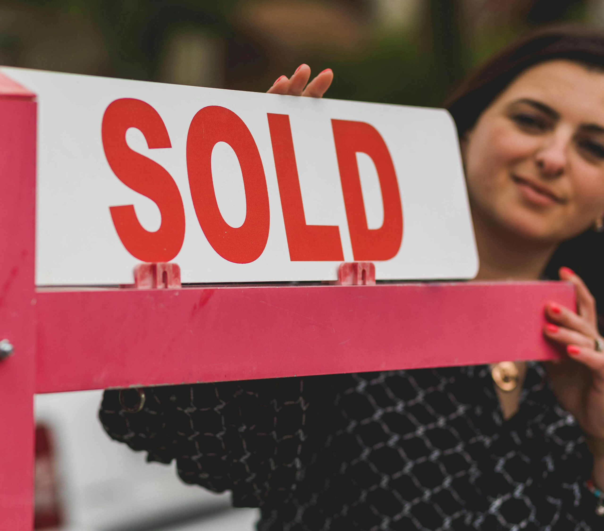 woman inserting Sold sign